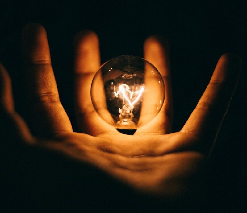 clear glass bulb on human palm