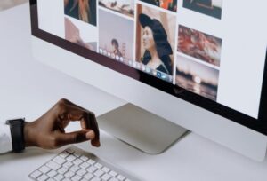 Man working on computer in modern office, viewing photography website. Clean and tech-focused environment.