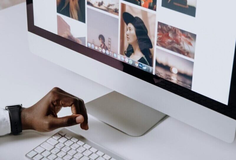 Man working on computer in modern office, viewing photography website. Clean and tech-focused environment.