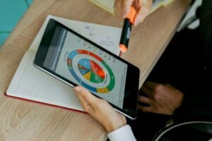 Business professionals analyzing data on tablet during a meeting with laptops and charts.