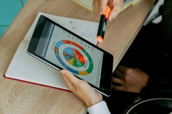 Business professionals analyzing data on tablet during a meeting with laptops and charts.