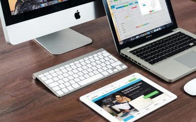A sleek office desk setup featuring Apple devices: iMac, MacBook, and iPad.