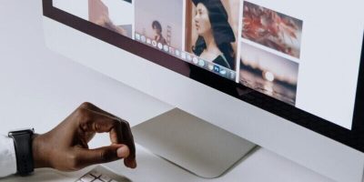 Man working on computer in modern office, viewing photography website. Clean and tech-focused environment.