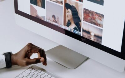 Man working on computer in modern office, viewing photography website. Clean and tech-focused environment.