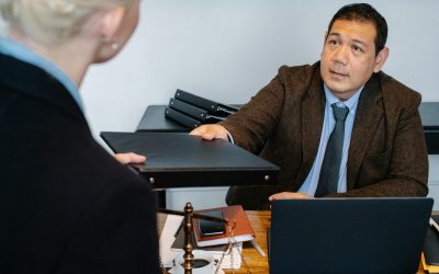 A professional business interaction at a desk with document exchange.