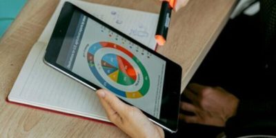 Business professionals analyzing data on tablet during a meeting with laptops and charts.