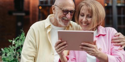 Happy senior couple using a tablet together, enjoying outdoor leisure time.