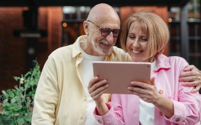 Happy senior couple using a tablet together, enjoying outdoor leisure time.